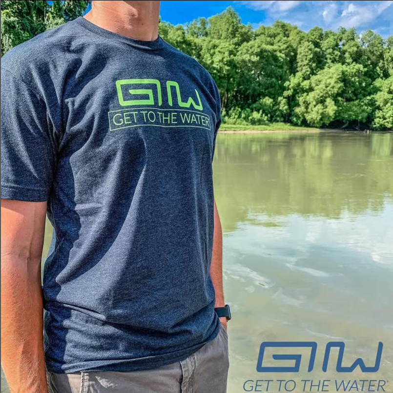 Founder wearing a Get To The Water t-shirt by a calm river on a sunny day